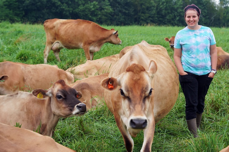 Gillian Newbold stands in a field among the UNH Organic Dairy Research Farms Jersey cows.